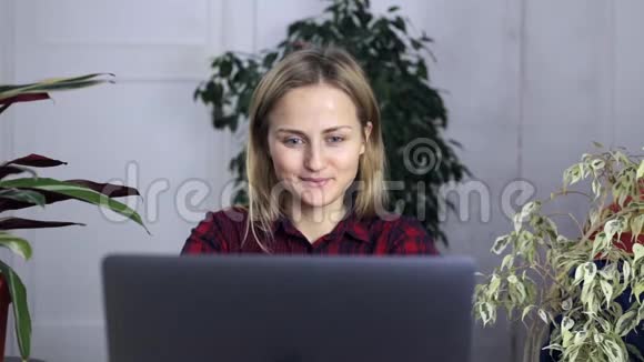 年轻女孩对她的工作成果感到满意她双手坐在笔记本电脑旁这显示了她的喜悦和成功视频的预览图