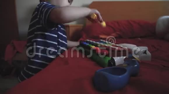 可爱的两岁男孩在卧室里玩木琴视频的预览图