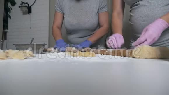戴着亮手套的女人把面团擀在桌子上自制食物馄饨饺子怀孕女孩做面团视频的预览图