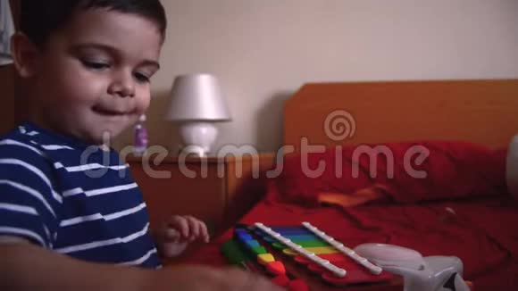 可爱的两岁男孩在卧室里玩木琴视频的预览图