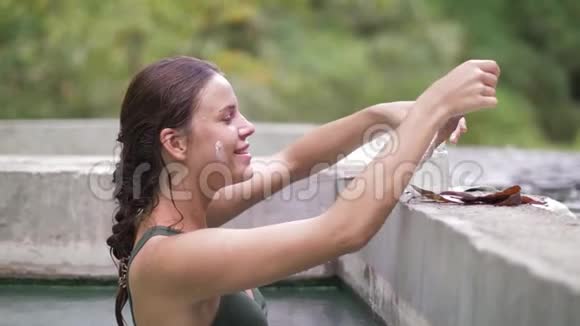 快乐的女人洗热水澡收集面膜的愈合泥年轻女子享受天然温泉视频的预览图
