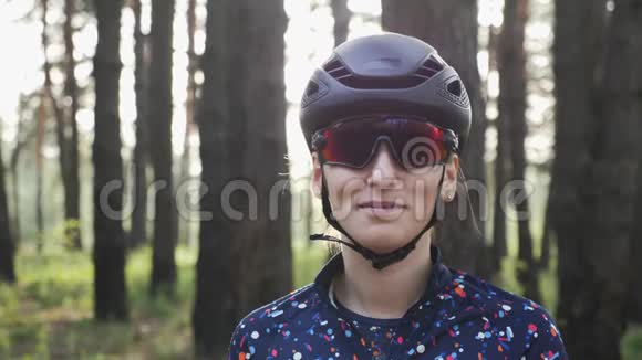 快乐骑自行车女孩拉链在蓝色球衣前训练前戴黑色头盔和眼镜自行车的概念慢动作视频的预览图