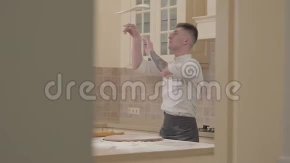 专业厨师在厨房里用两只手在空中旋转和投掷比萨饼面团视频的预览图