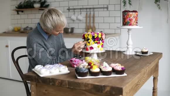 糖果厨师为假期装饰订单头发灰白的女人用小花装饰蛋糕视频的预览图