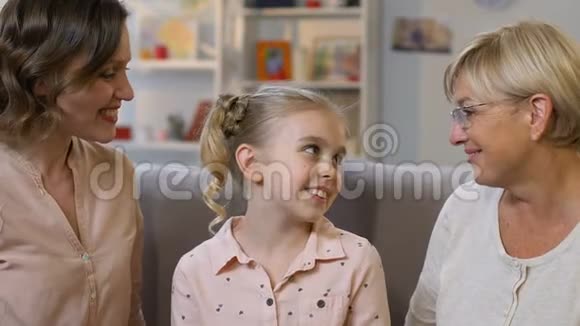 母亲和奶奶亲吻领养的女孩幸福的孩子拥抱新的爱的家庭视频的预览图