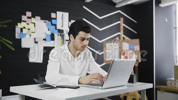 放大他桌上的英俊商人在手提电脑键盘上打字视频的预览图