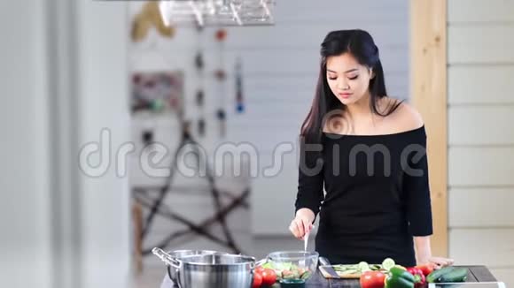 可爱的亚洲年轻女人在厨房里做饭吃新鲜的健康食品视频的预览图