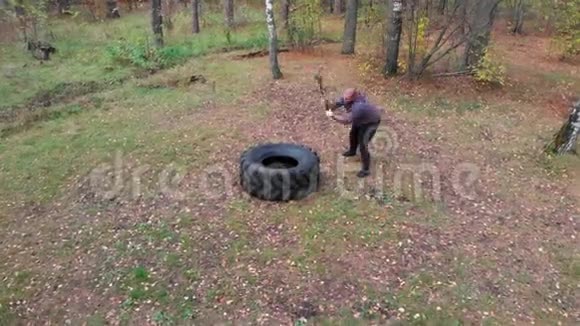 在秋天的森林里强壮的人用沉重的锤击打卡车的轮胎视频的预览图