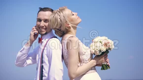 一对漂亮的新婚夫妇新郎背靠背站着微笑着看着镜头背景视频的预览图