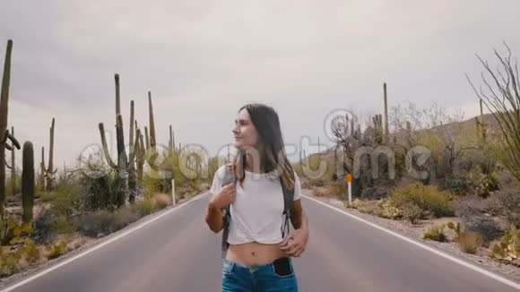 在仙人掌沙漠国家公园路上散步的年轻迷人的快乐旅游女性用智能手机拍照视频的预览图