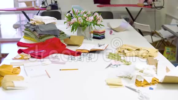 拍摄了一个阳光明媚的时装设计工作室桌子上有各种与缝纫相关的物品和五颜六色的织物视频的预览图