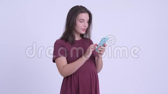 快乐的年轻美丽的孕妇用电话得到好消息视频的预览图