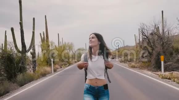 美国亚利桑那州仙人掌沙漠国家公园路上一位年轻的美丽的快乐的年轻的快乐的旅游女游客朝镜头走去视频的预览图
