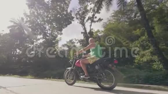 骑摩托车的人骑着摩托车在道路上行驶绿树成荫成熟男人骑摩托车上路视频的预览图