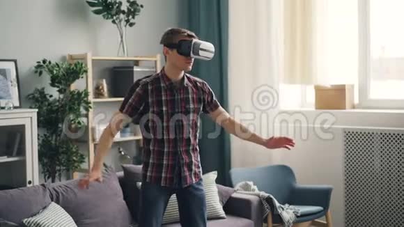 穿休闲服装的成年男子则集中在虚拟现实中的游戏中戴着虚拟现实眼镜站在家里戴着设备和视频的预览图