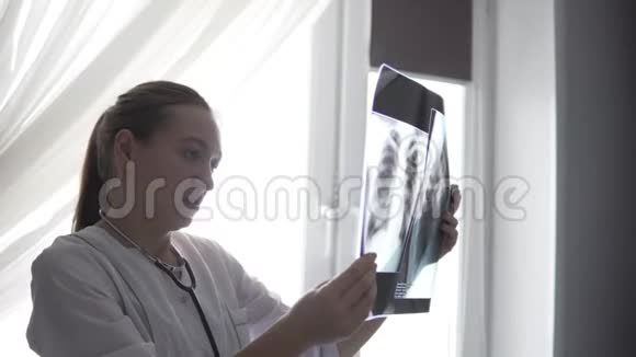 一位女医生站在窗边检查一张x光视频的预览图
