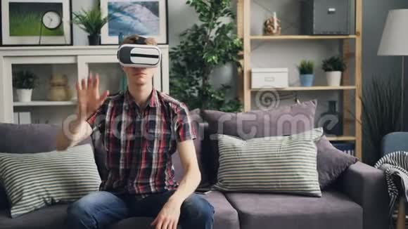 好看的男人头发白皙玩虚拟现实眼镜移动手和头戴耳机他是视频的预览图
