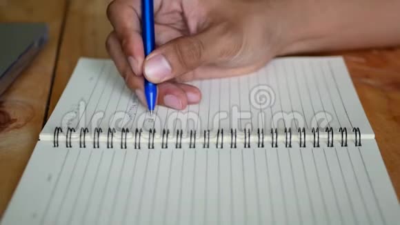 一个男人手在桌子上的笔记本上写字旁边有一个笔记本视频的预览图