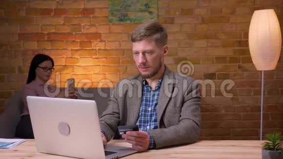 成人商人在办公室内用信用卡在笔记本电脑上网上购物的特写镜头女性雇员视频的预览图
