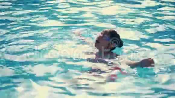 女孩在游泳池的背面游泳在游泳池的特殊眼镜里游泳游泳眼镜视频的预览图
