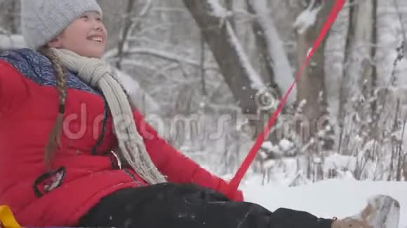 一个快乐的女孩在吐布上沿着一条白色的雪道滚动在自由的飞翔中欢笑圣诞节假期有趣的游戏视频的预览图