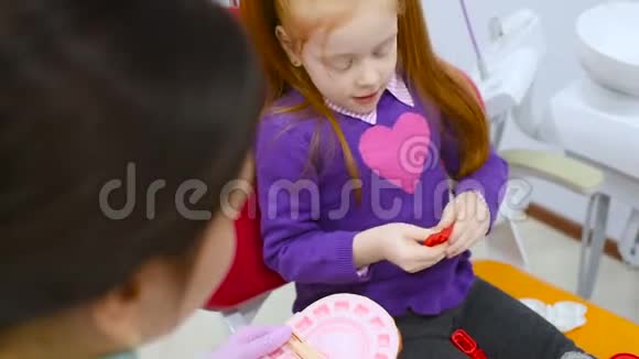 儿童牙医和病人一个红头发的小女孩玩玩具牙科器具用塑料制成视频的预览图