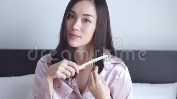 年轻快乐的美女在房间的镜子前用梳子梳头发视频的预览图