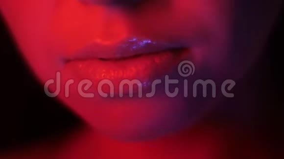 在夜总会里带有红色霓虹灯和bokeh背景的漂亮女性诱人嘴唇的特写镜头视频的预览图
