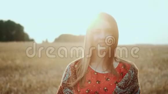 闭着脸美丽的女人在田野小麦上的夕阳农村微笑着看着镜头有机产品概念视频的预览图