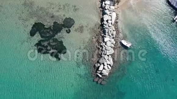 绿松石水中岩石码头的鸟瞰图一艘船停泊在码头旁边视频的预览图