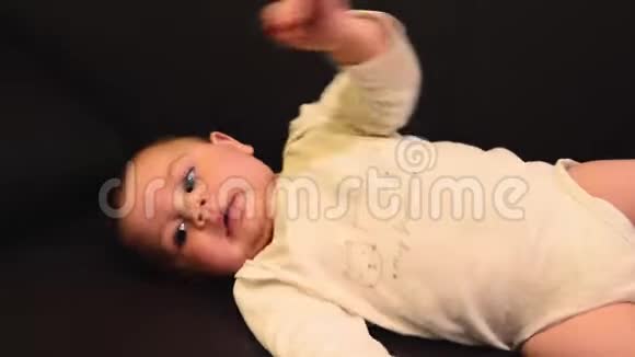 可爱的六个月大的男婴用脚踢试图从他的背部转向侧面视频的预览图
