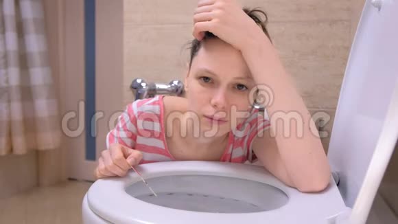 怀孕疲惫的女人正在厕所呕吐坐在家里的地板上看着相机视频的预览图