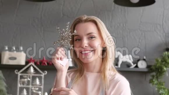 金发手握圣诞装饰和微笑特写镜头女孩展示一个产品拿着一个玩具球新年礼物视频的预览图