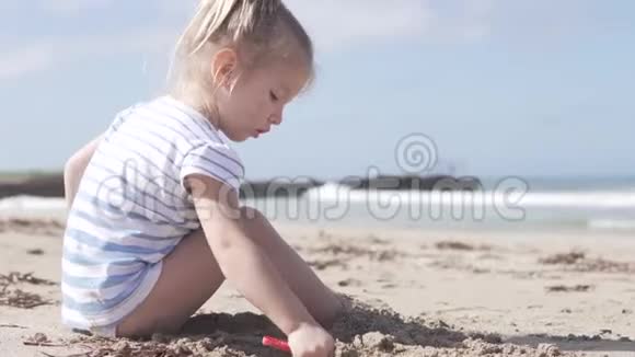 坐在海边沙滩上的可爱小女孩视频的预览图