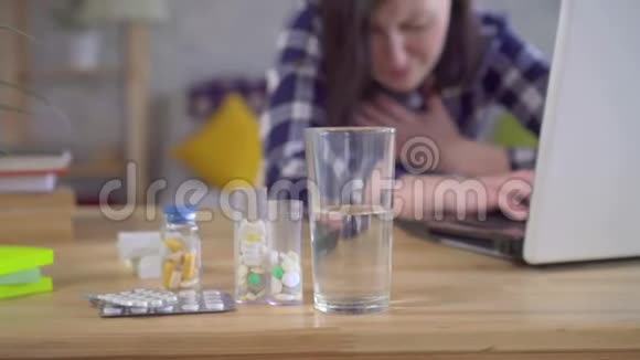坐在手提电脑上喝感冒药的年轻女子视频的预览图
