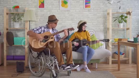 轮椅上的残疾青年吉他手和弹吉他的年轻女子视频的预览图