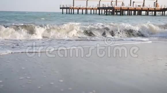 日落时大海的兴奋波浪在码头背景的沙滩上拍打视频的预览图