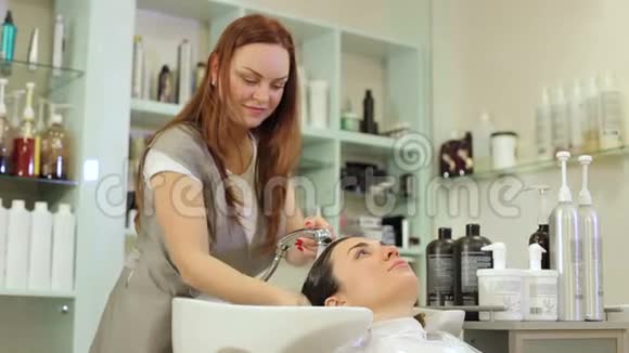 理发师在一家美容院给顾客洗头发视频的预览图