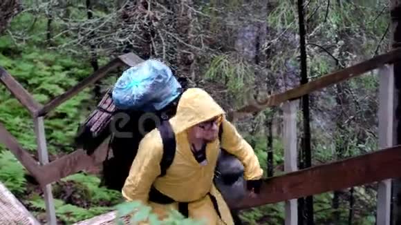 在森林运动中探险库存录像有着巨大装备和背包的人探索环境并爬上楼梯视频的预览图