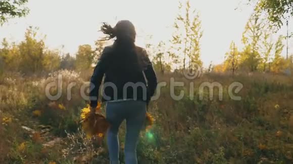 年轻的女人穿过秋天的森林手里拿着一束黄色的叶子把它们扔掉女士很开心视频的预览图