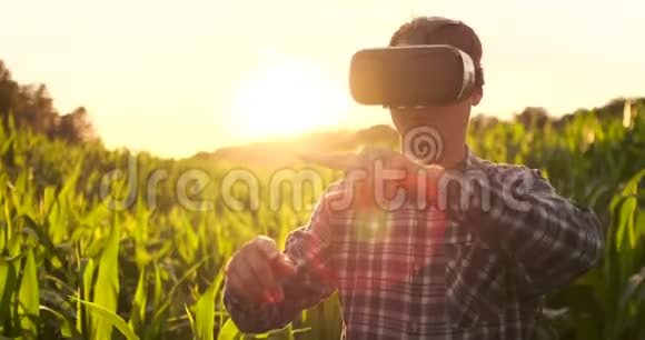 日落时分田里戴着虚拟现实眼镜的男性农民控制着玉米灌溉系统视频的预览图