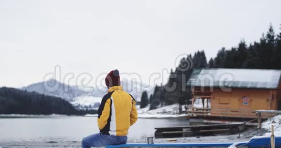 在一个大湖的中央在一个木屋的旁边一个人坐在一艘蓝色的小船上沉思着视频的预览图