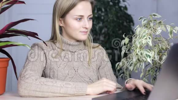穿着温暖舒适毛衣的女生在笔记本电脑后面工作视频的预览图