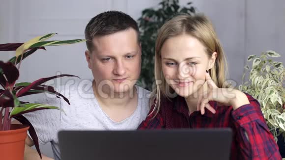 一个年轻人和一个女孩选择了一个新家坐在笔记本显示器后面视频的预览图