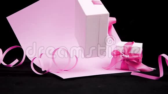 在粉红色和黑色背景上呈现带有粉红色丝带的盒子360度旋转无缝循环零重力视频的预览图