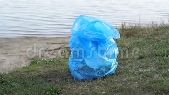 河附近的公园里装满垃圾的蓝色塑料袋视频的预览图