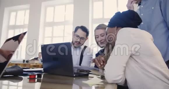 多民族专业营销公司经理在现代LOFT办公桌上合作笔记本电脑讨论工作视频的预览图