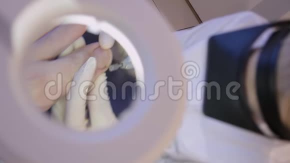 皮肤科医生与一个病人拇指指甲通过美容放大镜的视角特写镜头五金修脚视频的预览图