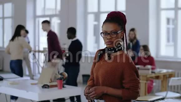 年轻的非洲商业女性戴着眼镜摆出严肃和压力然后微笑在时髦的阁楼办公室的肖像视频的预览图