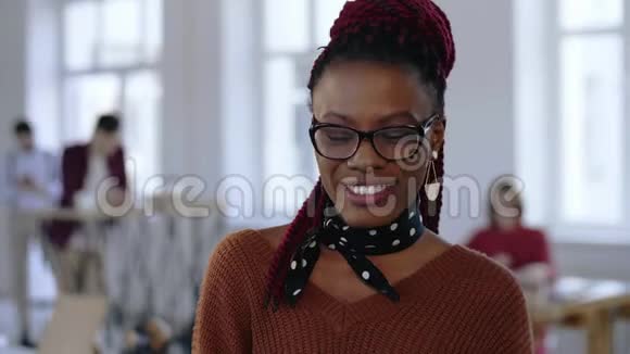 为年轻漂亮的黑色设计专家商务女性戴着智能眼镜微笑着在光办公室视频的预览图
